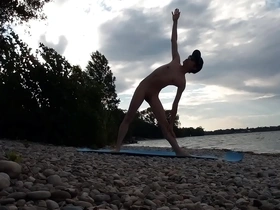 A skinny naturist boy performs yoga outdoors at a naturist beach.
